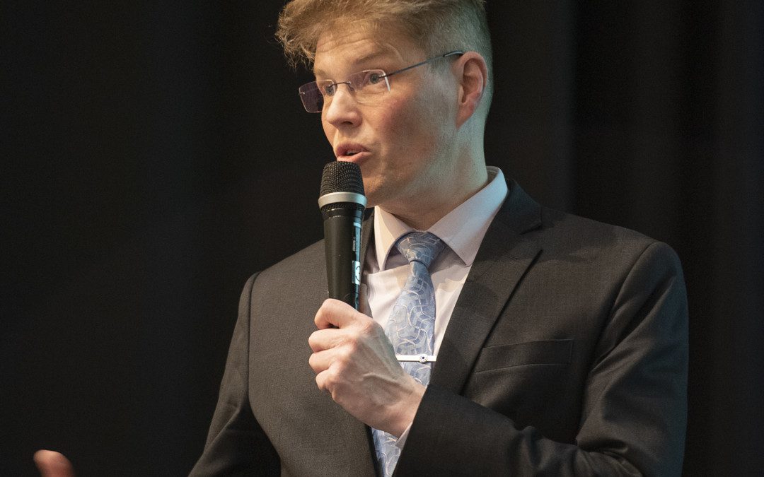 Kunnanjohtajaehdokas Jarkko Määttänen puhuu mikrofoniin mustaa taustaa vasten.