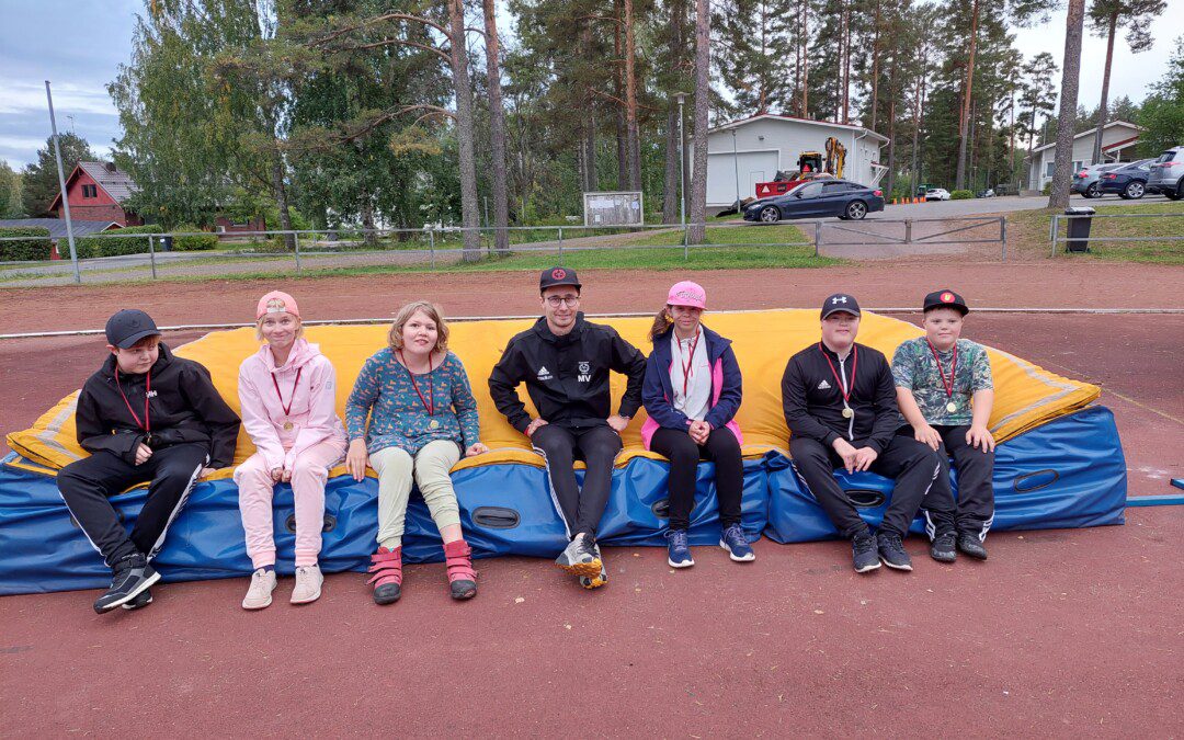 Muuramen Yrityksen soveltavan yleisurheilukerhon lapset ja seuran juniorivastaava Miikka Vitikainen, joka toimi ryhmän valmentajana. Kaikki istuvat yleisurheilukentällä hyppypatjan päällä