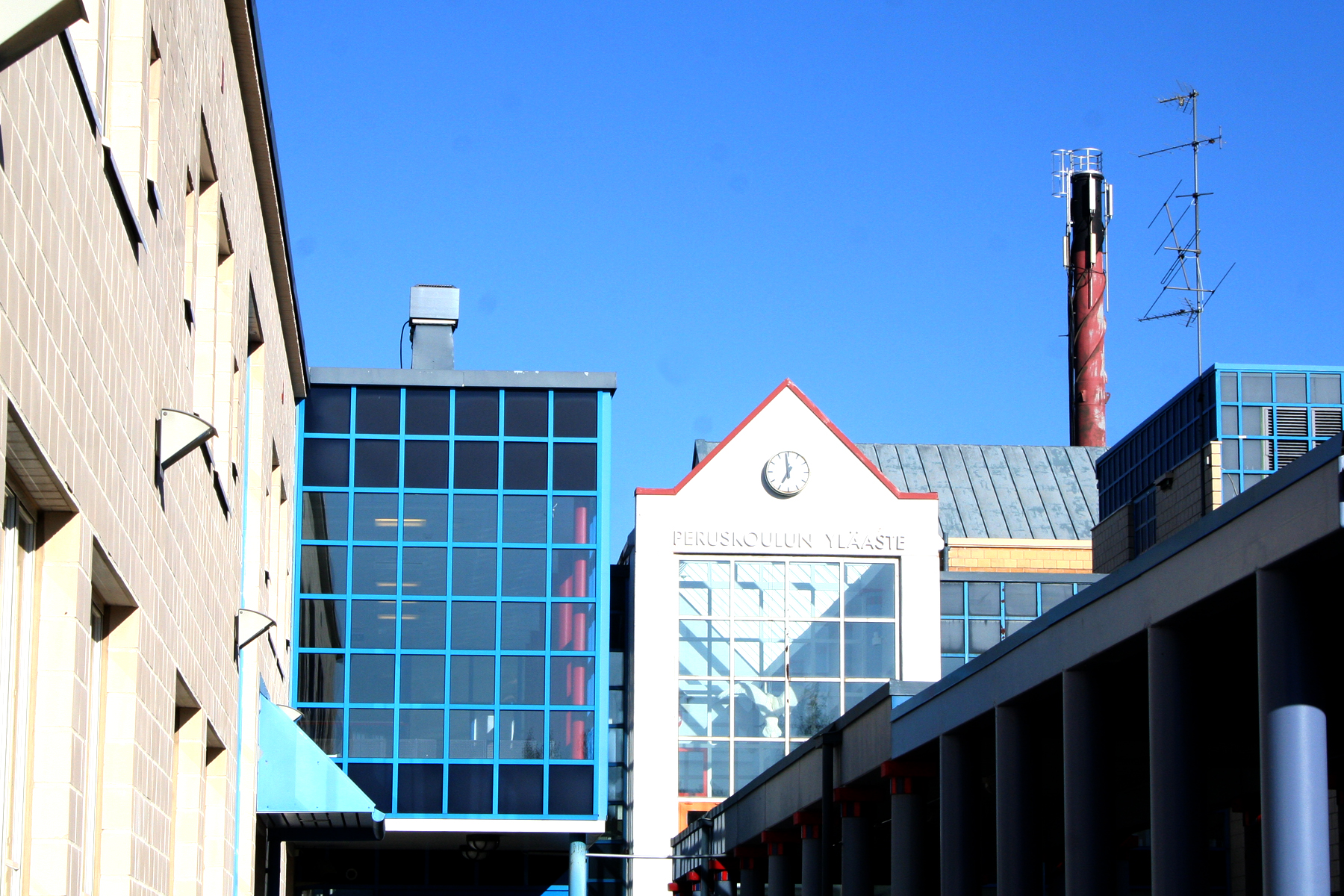 Kuvassa Nisulanmäen koulurakennuksen julkisivua ja taustalla näkyy korkea piippu.