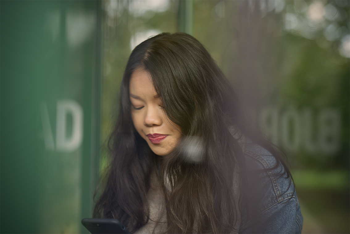 Omaolo-kuvitus:  puhelinta katsova nainen istumassa bussipysäkillä.